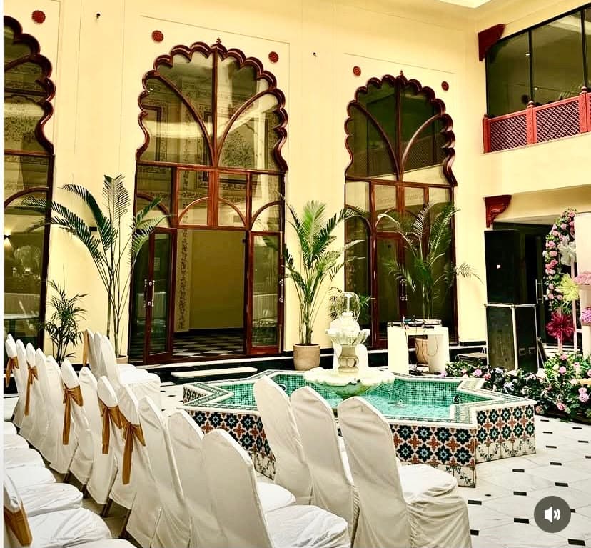 Courtyard banquet setup with celebration seating facing the central fountain and triple cusped portals